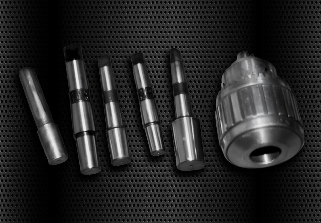 Precision machining tools and drill bits displayed on a black perforated surface, showcasing high-quality metal craftsmanship and industrial equipment for manufacturing and metalworking.