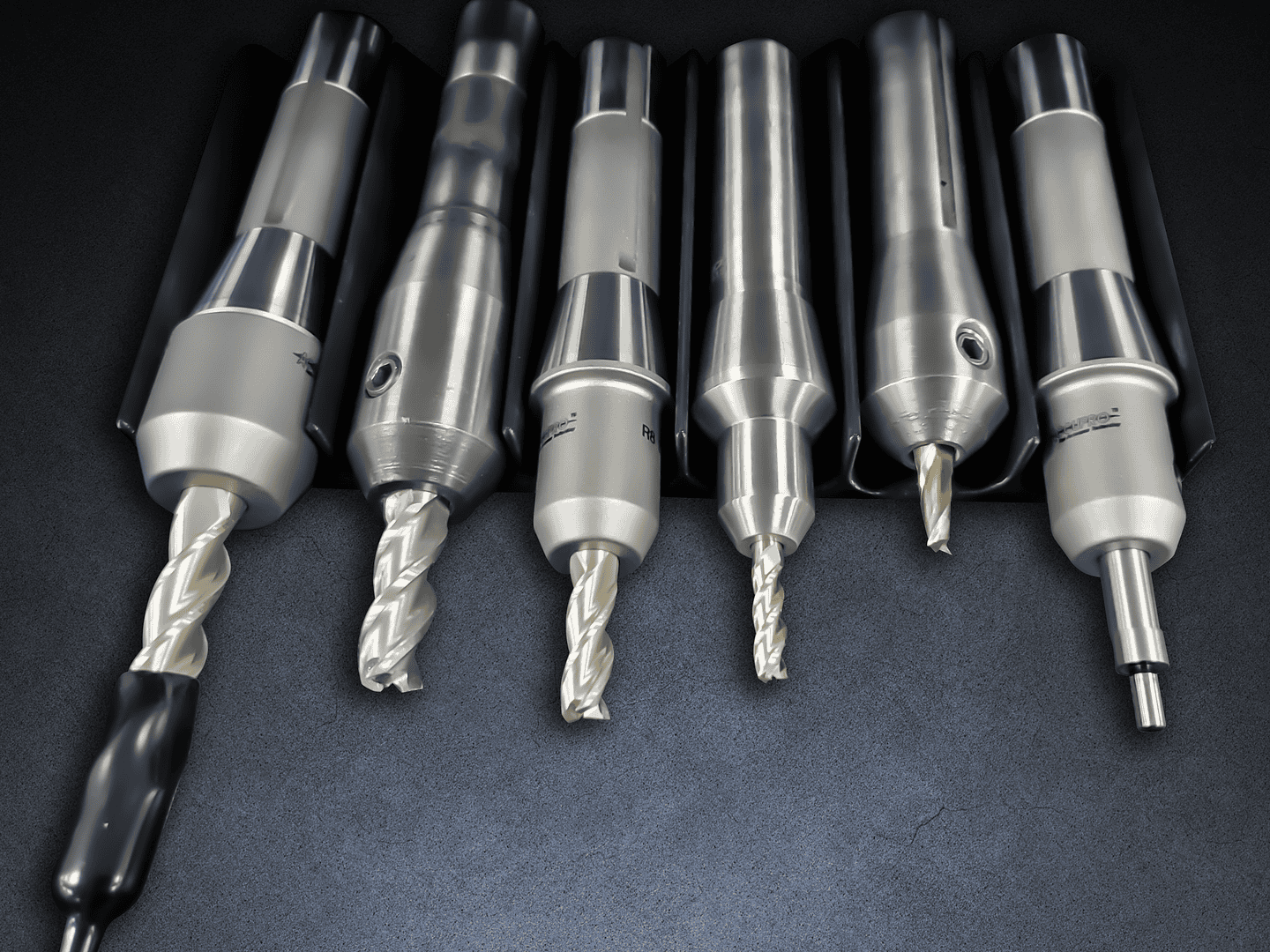 Drill bits and machining tools displayed on a black surface for industrial manufacturing and precision engineering.
